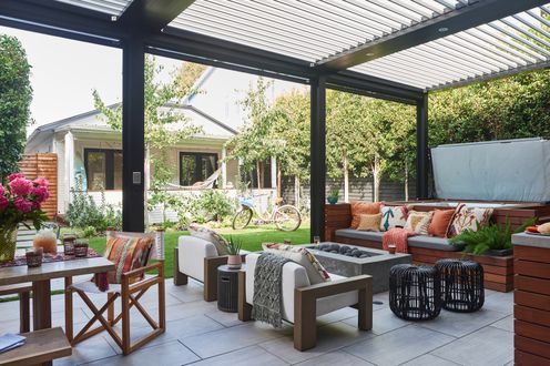 outdoorpatio with director chairs and benches around dining table; seating area with rectangular stone firepit and built-in bench seating in front of raised hot tub.