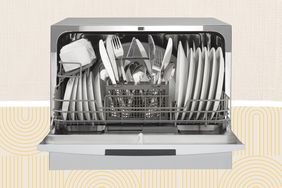 An open countertop dishwasher with dishes inside over a tan patterned background.