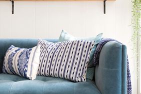 blue patterned pillows on velvet midcentury sofa with open shelving